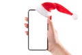 Female hand holding mobile smart phone with santa hat isolated on white background. Blank white screen. Concept of Christmas Royalty Free Stock Photo