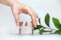 Female hand holding mockup unbranded plastic cosmetic tube. Cosmetics on the background of green plants. Skincare and beauty Royalty Free Stock Photo