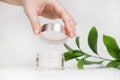Female hand holding mockup unbranded plastic cosmetic tube. Cosmetics on the background of green plants. Skincare and beauty Royalty Free Stock Photo