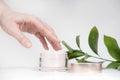 Female hand holding mockup unbranded plastic cosmetic tube. Cosmetics on the background of green plants. Skincare and beauty Royalty Free Stock Photo