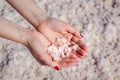 Female hand holding natural salt crystals on the background of a salt lake