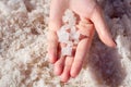 Female hand holding natural salt crystals on the background of a salt lake