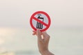 Female hand holding No phone calls sign on the beach