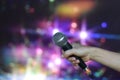 A female hand is holding one microphone against the colorful lights Royalty Free Stock Photo