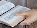 Female hand holding an open Holy Bible Book with golden pages, closeup Royalty Free Stock Photo