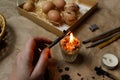 Female hand holding pen, pysachok, near flame and heating it. Preparing for painting Ukrainian Easter eggs decorated Royalty Free Stock Photo