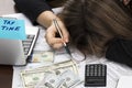 Female hand holding a pen and using calculator while filling in