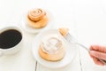 Female hand holding a piece of a cinnamon roll with a fork Royalty Free Stock Photo