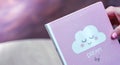 Female hand holding a pink diary with text DREAM BIG and nice cloudlet on a pink purple background. Inspiration and motivation Royalty Free Stock Photo