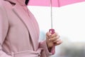 Female hand holding pink umbrella in rain closeup