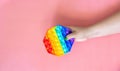 Female hand holding rainbow color antistress toy pop it