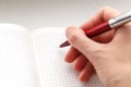 Female hand holding a red ballpoint pen on the empty notebook