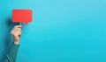 Female hand holding red speech bubble on blue background Royalty Free Stock Photo
