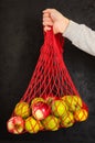 Female hand holding a string bag with fruits on black background. Eco friendly mesh bag - alternative to plastic bags Royalty Free Stock Photo