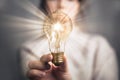 Female hand holding a shining light bulb, Great idea, innovation and inspiration, business concept background Royalty Free Stock Photo