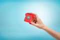 Female hand holding small red old fashioned telephone between her fingers on blue background Royalty Free Stock Photo