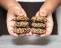 Female hand holding some healthy oatmeal hazelnut sesame peanut cookies in a bright kitchen