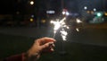 Female hand holding sparklers in the street. Close up of woman holding sparkler on the street. Closeup of Girl with Royalty Free Stock Photo