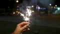 Female hand holding sparklers in the street. Close up of woman holding sparkler on the street. Closeup of Girl with Royalty Free Stock Photo