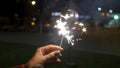 Female hand holding sparklers in the street. Close up of woman holding sparkler on the street. Closeup of Girl with Royalty Free Stock Photo