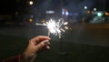 Female hand holding sparklers in the street. Close up of woman holding sparkler on the street. Closeup of Girl with Royalty Free Stock Photo