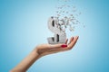 Female hand holding stone concrete dollar sign shattering into pieces on blue background