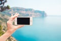 Female hand holding telephone on beautiful landscape background. Woman holding smartphone on ocean background. Travelling concept Royalty Free Stock Photo