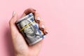 Female hand holding tightly a rolled bundle of money. Top view of one hundred dollars on colorful background. Investment concept Royalty Free Stock Photo