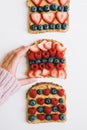 Female hand holding a toast with whole grain bread, peanut butter, strawberry, blueberry, raspberry