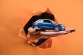 female hand holding a toy car on an orange background Royalty Free Stock Photo