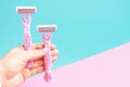 Female hand holding two disposable razors on blue pink background Royalty Free Stock Photo