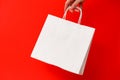 Female hand holding white blank shopping bag isolated on red background. Black friday sale, discount, recycling Royalty Free Stock Photo