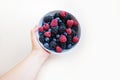 Female hand holding a white bowl with a mix of fresh summer berries - blackberry, blueberry, raspberry Royalty Free Stock Photo