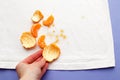 Female hand holding white clothes with ditry stains from fruits mandarin on purple very peri background