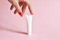 Female hand holding white cosmetic product tube. Blank plastic container for cream, lotion, toothpaste, nourishing or moisturizing Royalty Free Stock Photo