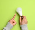 Female hand holding white glass lamp, green energy Royalty Free Stock Photo