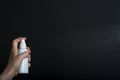 Female hand holding white sprey bottle and spray on dark background Royalty Free Stock Photo