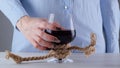 female hand holding wine glass is tied with a jute rope. The concept of alcohol dependence. Royalty Free Stock Photo