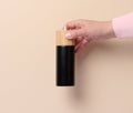 Female hand holding a wooden pepper mill on a beige background Royalty Free Stock Photo