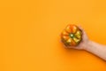 Female hand holding yellow bell pepper on orange background Royalty Free Stock Photo