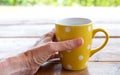 Female hand holding yellow polka dot mug