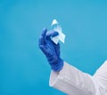 Female hand holds blue silk ribbon in the shape of a loop on a blue background Royalty Free Stock Photo