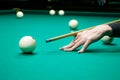 Female hand holds a cue for striking the white cue ball. Woman p Royalty Free Stock Photo