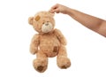 Female hand holds the ear of a big beige cute teddy bear with patches Royalty Free Stock Photo