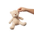 Female hand holds the ear of a small beige cute teddy bear with patches Royalty Free Stock Photo