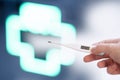 Female hand holds an electronic thermometer on a pharmacy cross bokeh background.