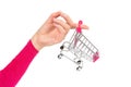 Female hand holds an empty miniature shopping cart on one finger. Close-up shot, isolated on white