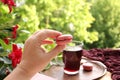 Female hand holds a french pasta cake in the garden, pomegranate, cherry juice, fruit drink in a glass mug, clematis flowers, Royalty Free Stock Photo