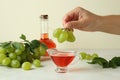 Female hand holds grape over the sauce boat with vinegar Royalty Free Stock Photo