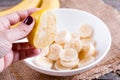 A female hand holds a lemon over a bowl with bananas